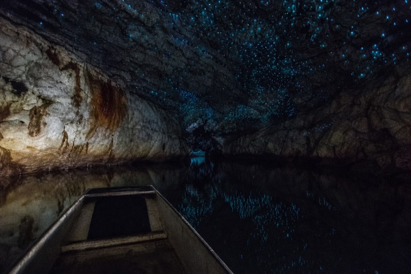 A boat on the underground river beneath the glowworms of the Waitomo Glowworm Caves