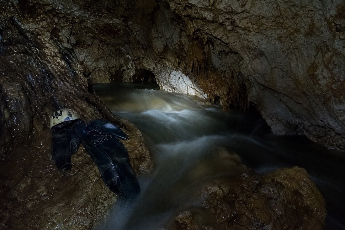 Another view at Waitomo: a low limestone cave passage half filled with fast dark water and an empty inner tube floating in an eddy