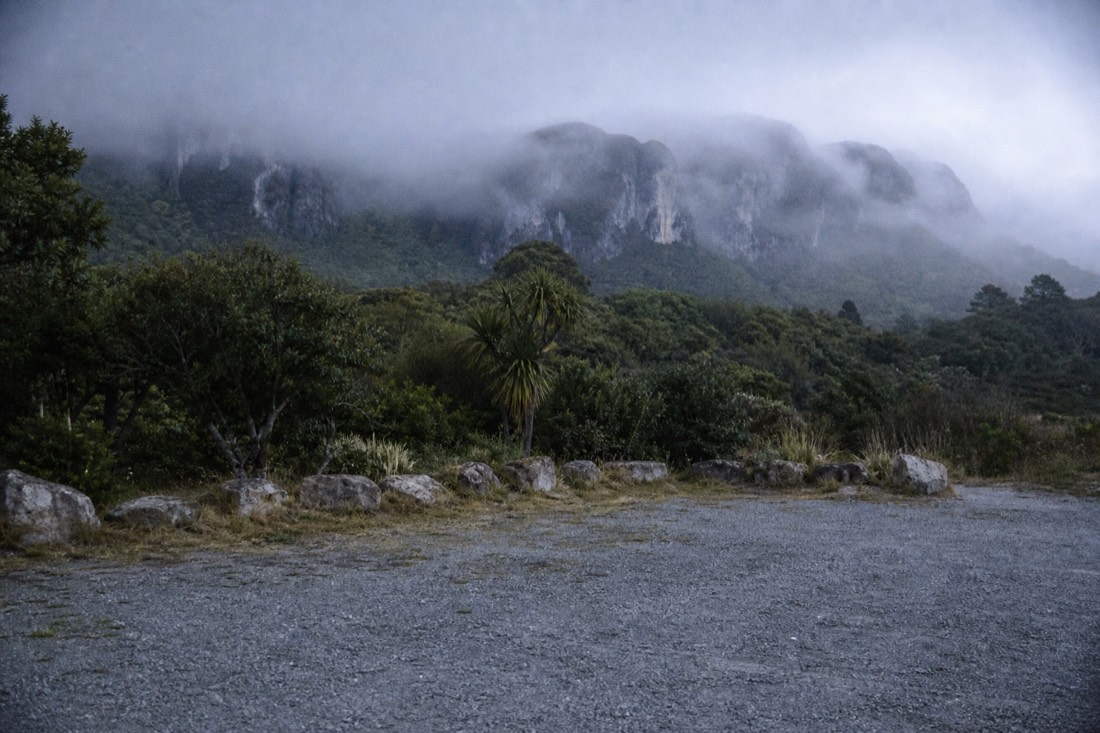 Another view at Waitomo: a dimly lit limestone cave passage with a formed walkway and handrail curving away into darkness